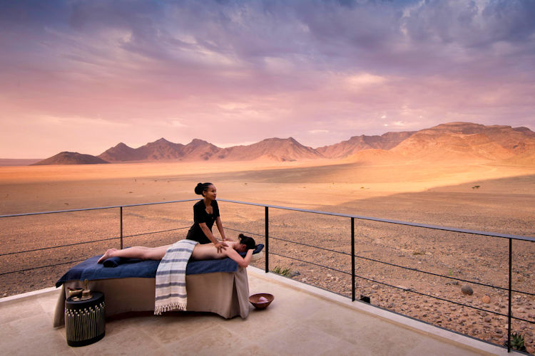 The image depicts a luxurious outdoor spa treatment pavilion set against the stunning backdrop of the African wilderness, featuring a couples massage setup with soft linens and aromatic candles. This serene space is perfect for a romantic safari getaway, offering breathtaking views of the landscape, ideal for couples seeking relaxation amidst nature.