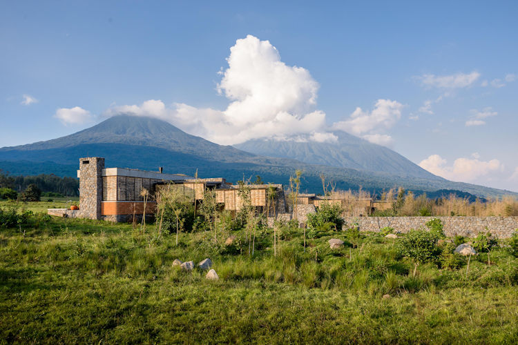 Luxury lodge thatched roof Volcanoes National Park volcanic mountains Rwanda eco-safari highland