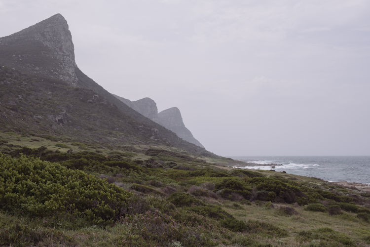The image depicts a dramatic clifftop lighthouse at Cape Point, overlooking the vast Atlantic Ocean that stretches to the horizon, showcasing the stunning coastal scenery of Cape Town. This iconic landmark is part of the Cape Peninsula, a popular tourist destination known for its breathtaking views and rich history.