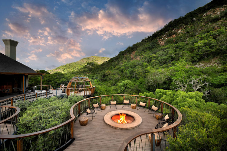 Glass-fronted luxury safari suite with private deck overlooking a rocky valley at sunset in the Eastern Cape