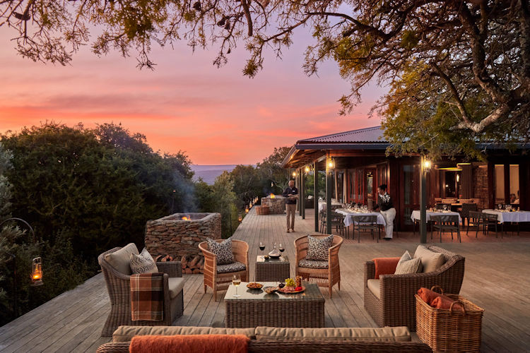 Colourful contemporary safari lodge lounge with large windows overlooking an Eastern Cape valley