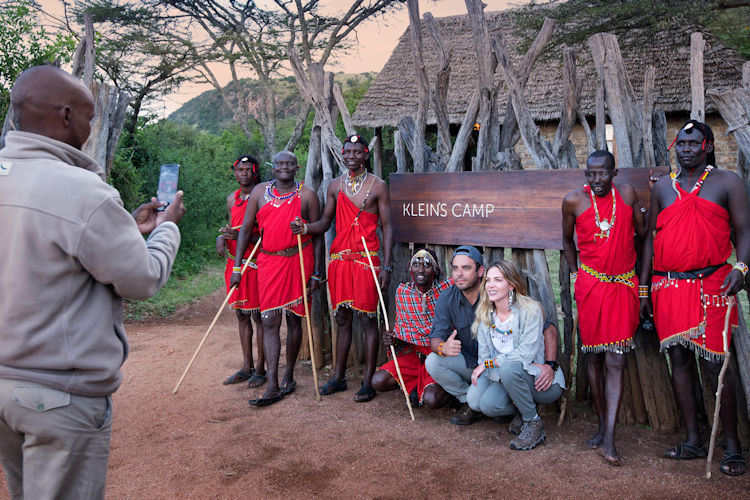 Visitors interacting with a local family in a Maasai village during a tanzania family safari.