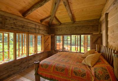 Cozy en-suite bedroom at Ragati Cabin with rustic furnishings and serene forest views