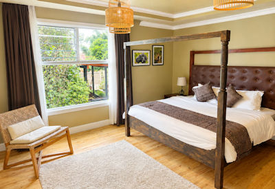 Tiloreza Volcanoes Ecolodge deluxe room queen bed en-suite bathroom warm earth tones Kinigi Musanze Rwanda