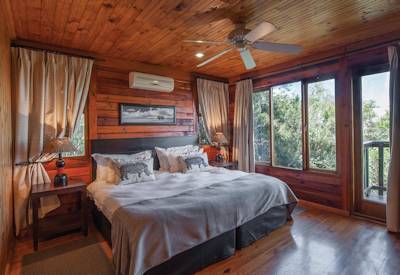 Air-conditioned log chalet suite with fireplace and king-size bed at Kariega Main Lodge Eastern Cape