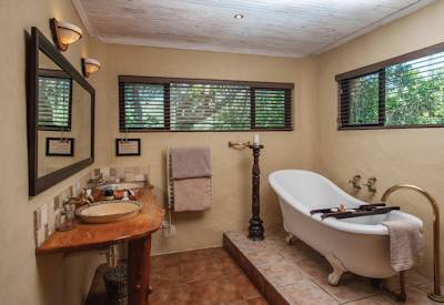 En-suite bathroom with ornate bath and double vanity at Kariega River Lodge Eastern Cape