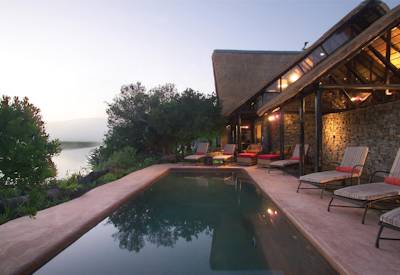 Swimming pool with sun loungers overlooking Bushman's River at Kariega River Lodge Eastern Cape