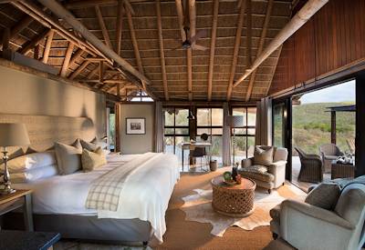 Thatched luxury safari lodge with weathered timber and stone walls at Kwandwe Great Fish River Lodge