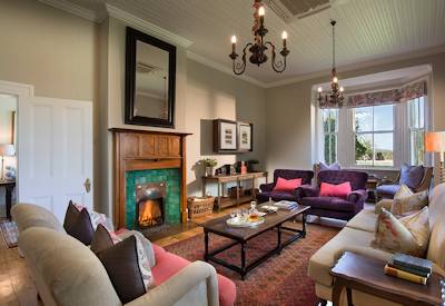 Spacious sitting room with comfortable chairs and fireplace at Kwandwe Uplands House Kwandwe