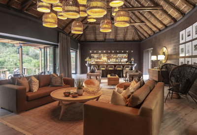 Indoor lounge with fireplace and fold-away glass walls at Shamwari Eagles Crag Lodge Eastern Cape