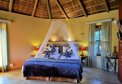 Luxury thatched safari suite with king-size bed at Sibuya Bush Lodge Sibuya Game Reserve
