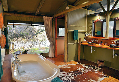 En-suite bathroom with bath and shower at Sibuya River Camp Sibuya Private Game Reserve