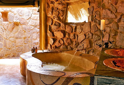 En-suite bathroom with large bathtub and outdoor shower at Jaci's Safari Lodge Madikwe
