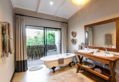 En-suite bathroom with bathtub and outdoor shower at Fugitives Drift Lodge KwaZulu-Natal