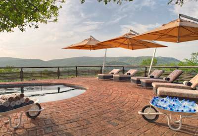 Shaded swimming pool with sun loungers at AndBeyond Phinda Mountain Lodge Phinda Game Reserve