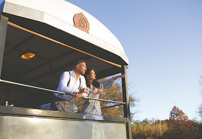 Couple on Rovos Rail open observation car balcony Southern Cross Safari sunset