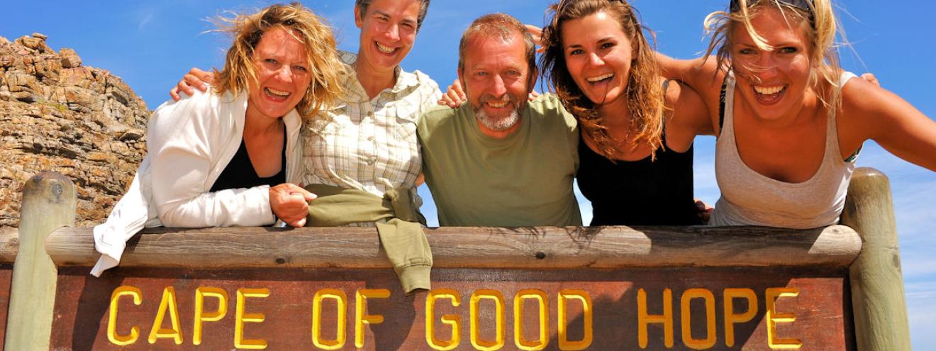 A group of travellers posing at the Cape of Good Hope sign on a South Africa overland safari along the Cape Peninsula