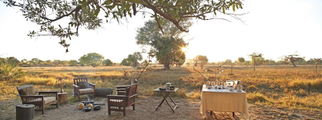 Luwi Bush Camp rustic grass and thatch chalets set under ancient mahogany trees on a dry riverbed