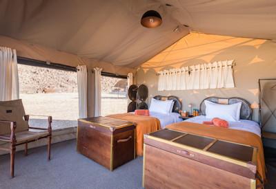 A desert camp with two family tents and tented guest rooms