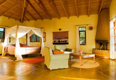 Ngorongoro Farm House large thatched suite four-poster bed fireplace veranda Tanzania