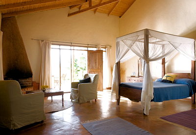 Ngorongoro Farm House bedroom central fireplace wood-beamed ceiling concrete floor Tanzania