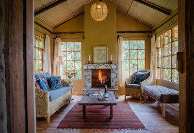 Mount Gahinga Lodge lounge fireplace refurbished gardens Mgahinga Uganda