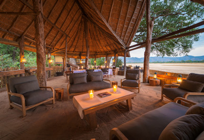 Open fronted luxury chalet interior featuring an elegant bed and sweeping views of the African wild at Chamilandu
