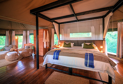 Spacious luxury safari tent interior with a high four-poster bed and private lagoon views at Chindeni Bushcamp