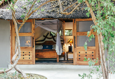 Private outdoor bathtubs and open-air showers built into the wild riverbank at Kaingo Camp