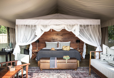 Spacious and airy luxury safari tent interior with a plush bed looking out at Kulandila Camp