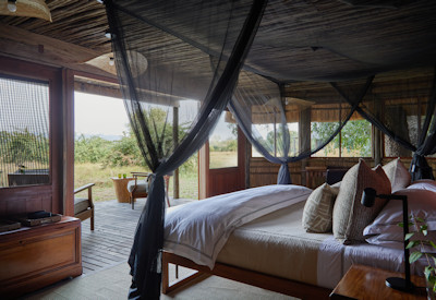 Cozy traditional African chalet interior with large open mesh windows at Kuyenda Bushcamp