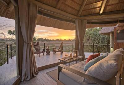 Spacious luxury suite interior featuring a comfortable bed and private viewing deck at Lion Camp