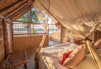 Comfortable and rustic chalet interior built naturally from grass and thatch at Luwi Bush Camp