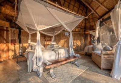 Spacious luxury canvas tent interior featuring a plush bed and elegant safari furnishings at Mchenja Camp
