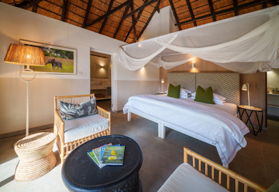 Comfortable and modern chalet interior featuring a plush bed and private lagoon facing veranda at Mfuwe Lodge