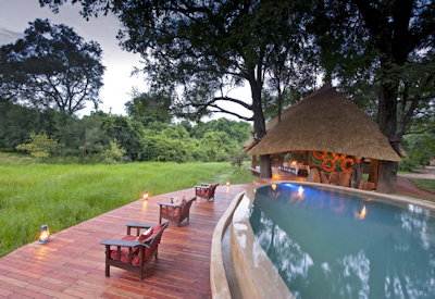 Refreshing main swimming pool set under the shade of ancient mahogany trees overlooking the lagoon at Nkwali Camp
