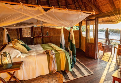 Spacious open-plan thatched chalet interior featuring comfortable beds and mosquito nets at Nsolo Camp