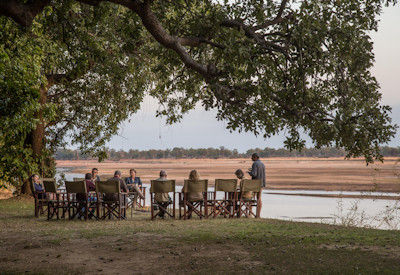 Safari guests enjoying fresh breakfasts by the river and candlelit dinners under the stars at Tafika Camp
