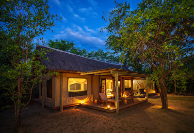 Sunken lounge deck and evening campfire boma area at Zungulila Bushcamp classic safari camp under the stars